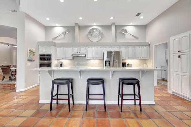 kitchen featuring a kitchen island, a kitchen bar, white cabinetry, and appliances with stainless steel finishes