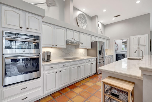 kitchen featuring backsplash, a high ceiling, white cabinets, sink, and appliances with stainless steel finishes