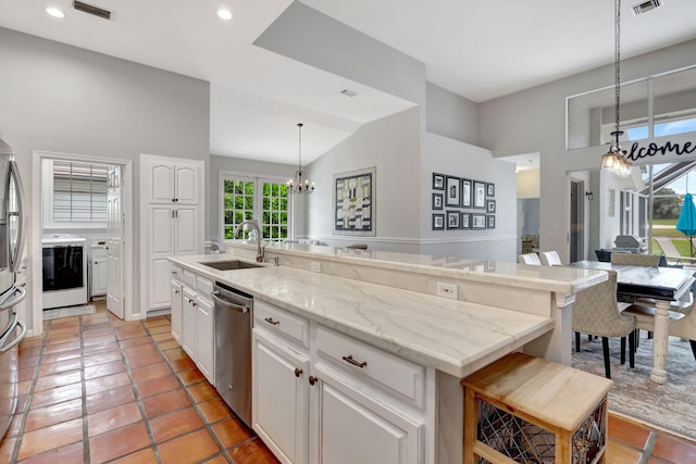 kitchen with dishwasher, sink, a kitchen breakfast bar, decorative light fixtures, and a kitchen island with sink