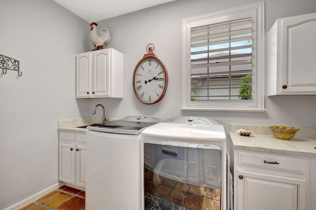 clothes washing area with washer and clothes dryer, cabinets, and sink