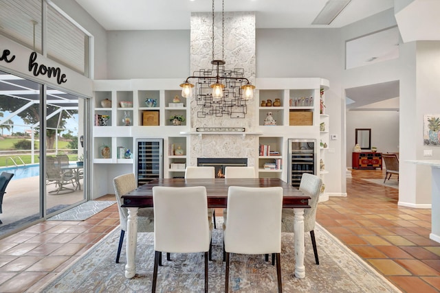 tiled dining area with built in shelves, a stone fireplace, and a high ceiling