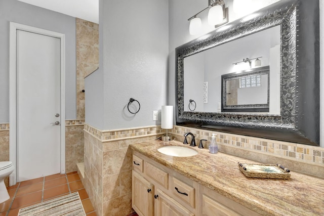 bathroom with tile patterned floors, vanity, toilet, and tile walls