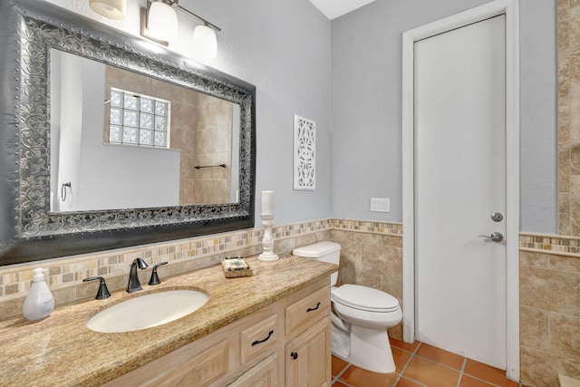 bathroom with tile patterned flooring, vanity, toilet, and tile walls