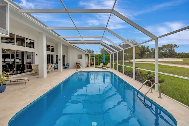 view of swimming pool with a lawn, glass enclosure, ceiling fan, and a patio area