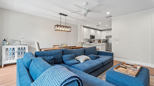 living room with light wood-type flooring and ceiling fan