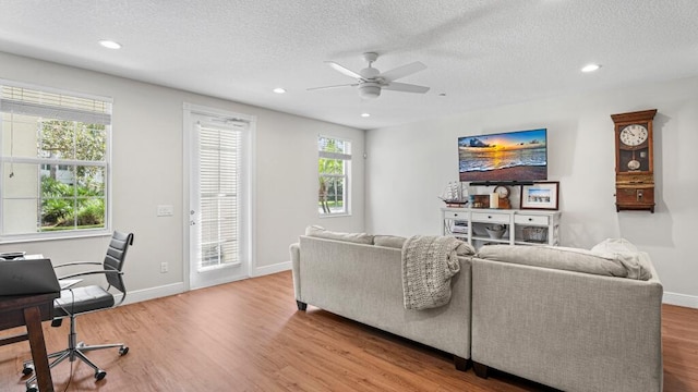 living room with a textured ceiling, hardwood / wood-style floors, and ceiling fan