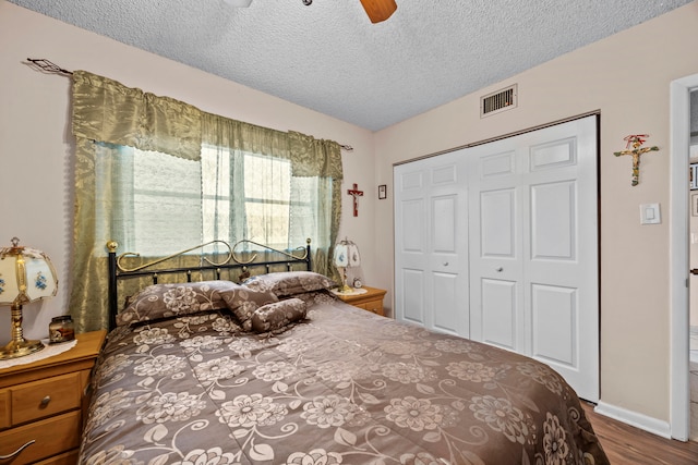 bedroom featuring hardwood / wood-style flooring, a textured ceiling, ceiling fan, and a closet