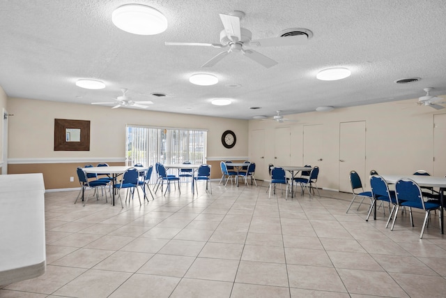 tiled dining space with ceiling fan and a textured ceiling