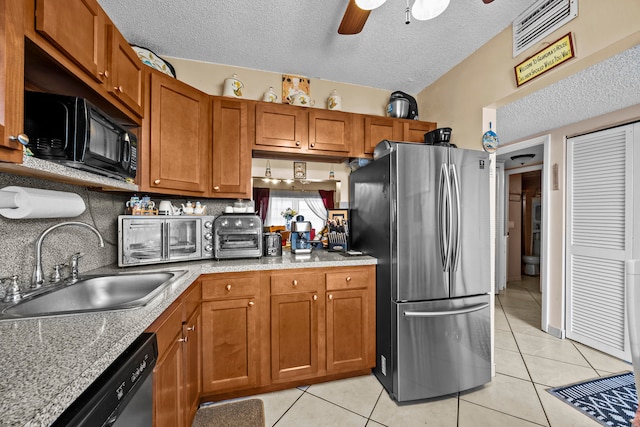 kitchen featuring appliances with stainless steel finishes, a textured ceiling, sink, and light tile patterned floors