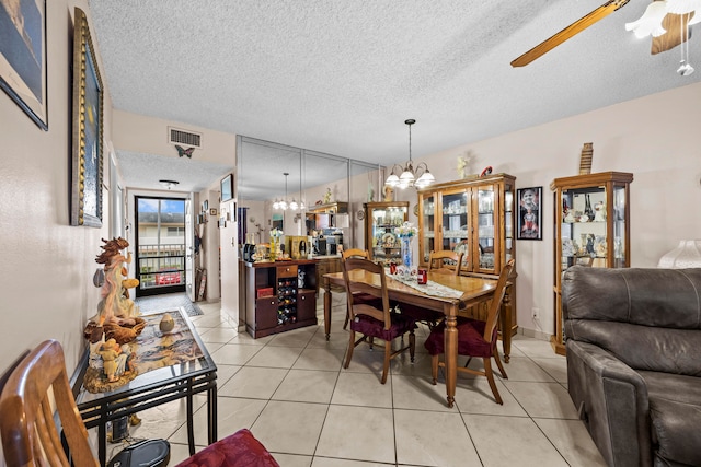 dining area with a textured ceiling, light tile patterned floors, and ceiling fan with notable chandelier