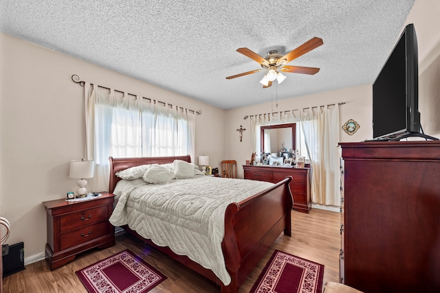 bedroom with hardwood / wood-style floors, ceiling fan, and a textured ceiling