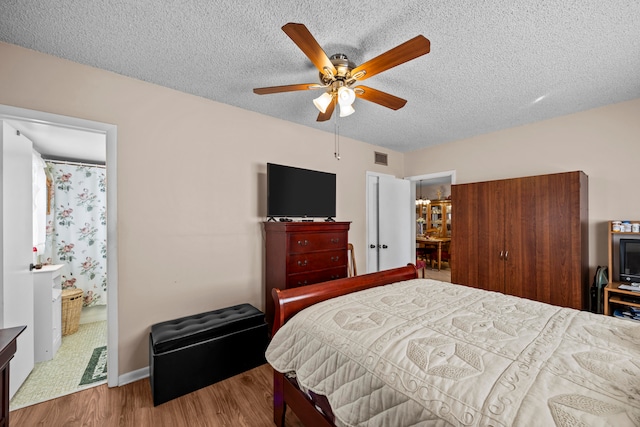 bedroom featuring a textured ceiling, ensuite bath, hardwood / wood-style flooring, and ceiling fan