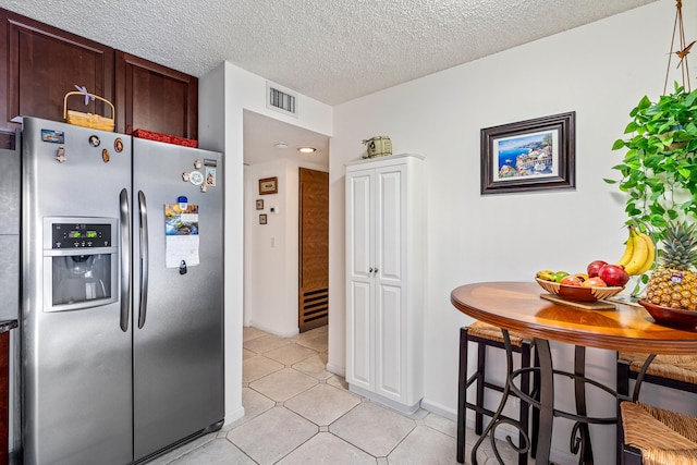 kitchen featuring dark brown cabinets, stainless steel fridge with ice dispenser, a textured ceiling, and light tile patterned floors