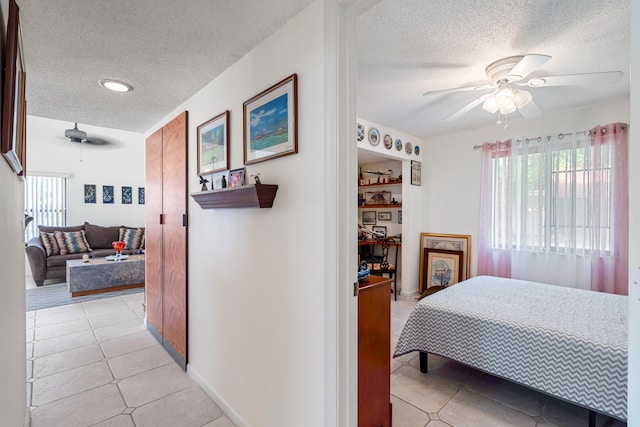 tiled bedroom featuring ceiling fan and a textured ceiling