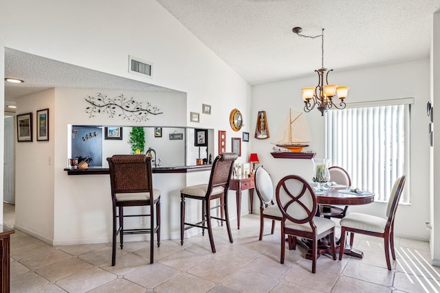 dining area featuring a notable chandelier, a textured ceiling, sink, and light tile patterned flooring