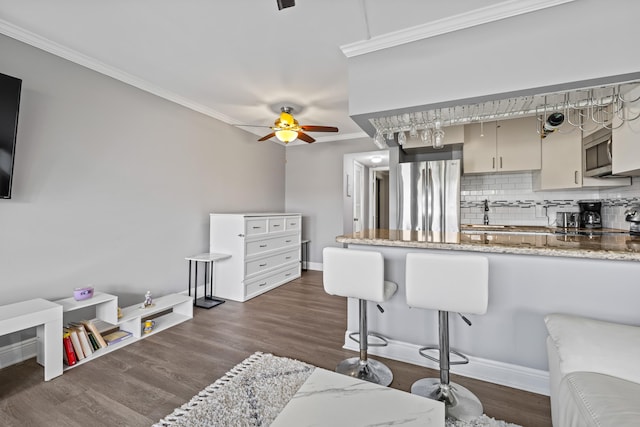 kitchen featuring appliances with stainless steel finishes, dark hardwood / wood-style floors, light stone countertops, decorative backsplash, and ceiling fan