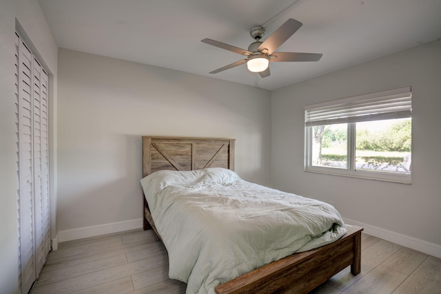 bedroom with light hardwood / wood-style flooring, ceiling fan, and a closet