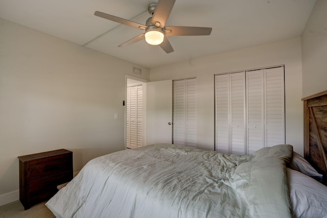 bedroom featuring light wood-type flooring, multiple closets, and ceiling fan