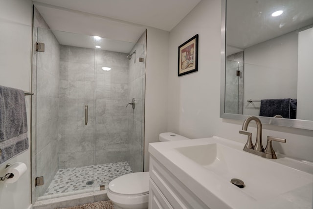 bathroom with a shower with shower door, vanity, and toilet