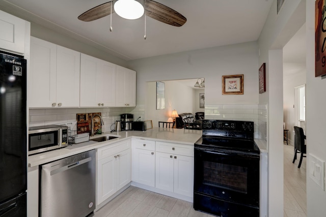 kitchen featuring white cabinets, sink, black appliances, and kitchen peninsula