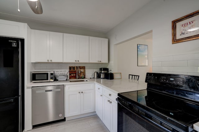 kitchen featuring light stone counters, black appliances, sink, tasteful backsplash, and white cabinetry