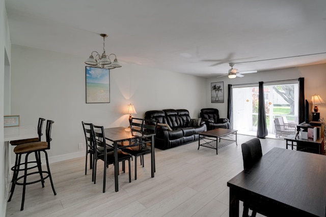 dining area with ceiling fan with notable chandelier and light hardwood / wood-style flooring