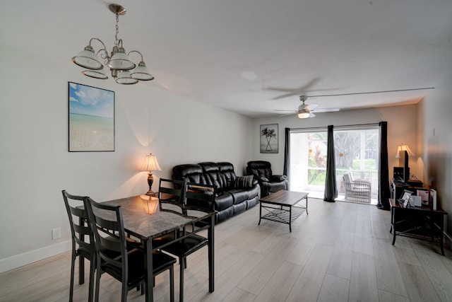 dining area with ceiling fan with notable chandelier and light hardwood / wood-style flooring