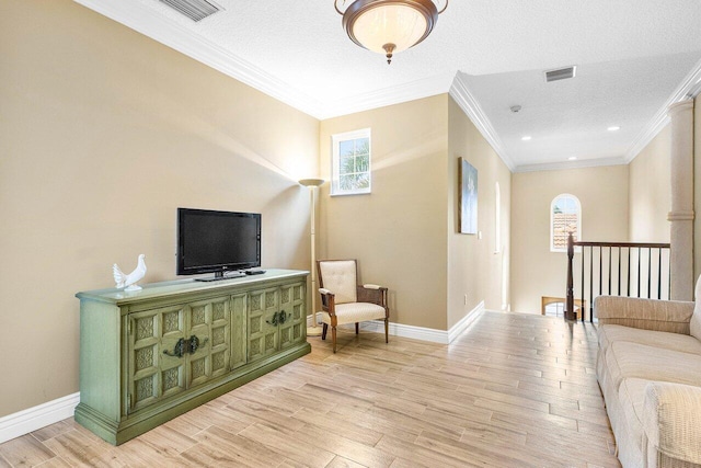 living room with a textured ceiling, light wood-type flooring, and crown molding