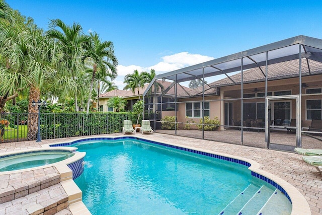 view of swimming pool featuring an in ground hot tub, glass enclosure, and a patio area