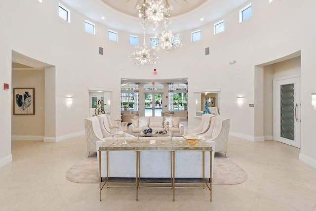 living room with french doors, a towering ceiling, a chandelier, a tray ceiling, and light tile patterned flooring