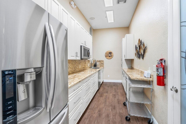 kitchen featuring light stone countertops, appliances with stainless steel finishes, dark hardwood / wood-style flooring, sink, and white cabinets