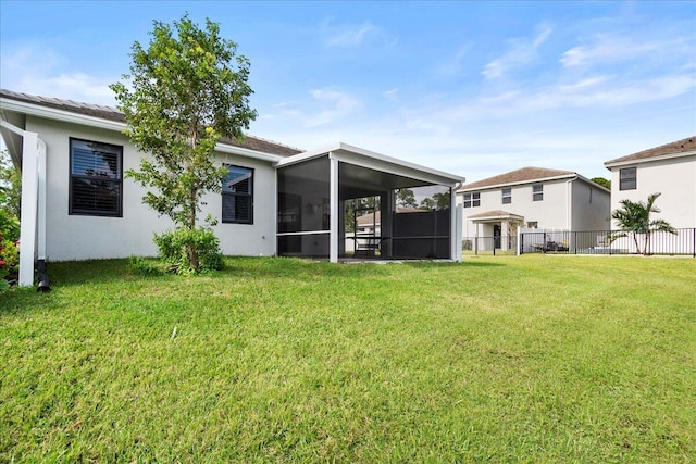 rear view of house with a sunroom and a yard