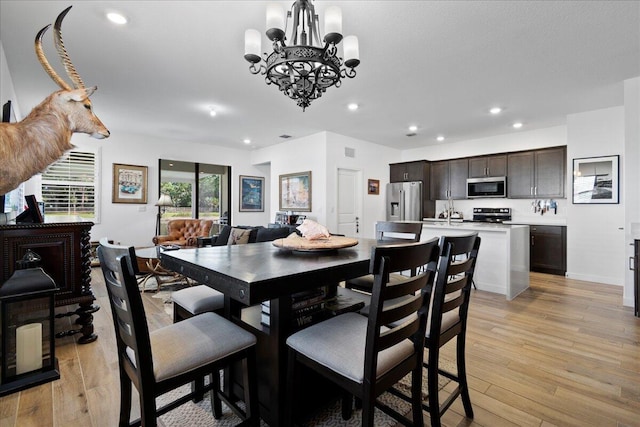 dining room featuring light wood-type flooring and a notable chandelier