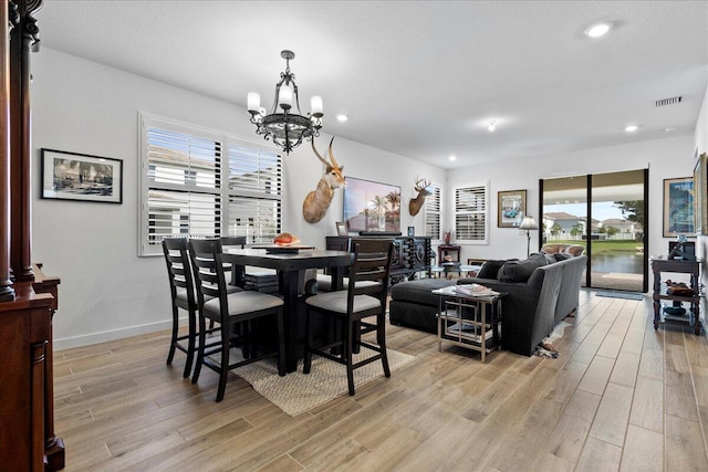 dining room featuring light wood-type flooring, a healthy amount of sunlight, and a chandelier