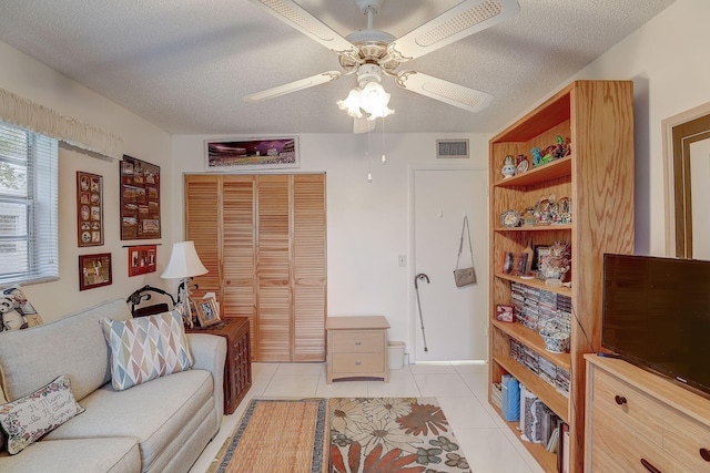 living room with a textured ceiling, light tile patterned floors, and ceiling fan