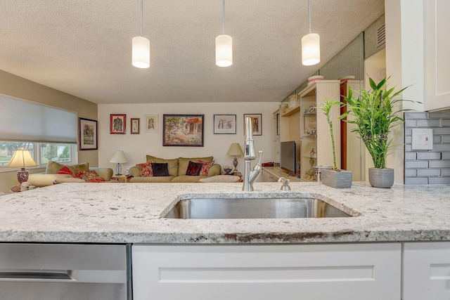 kitchen with tasteful backsplash, decorative light fixtures, light stone counters, and white cabinets