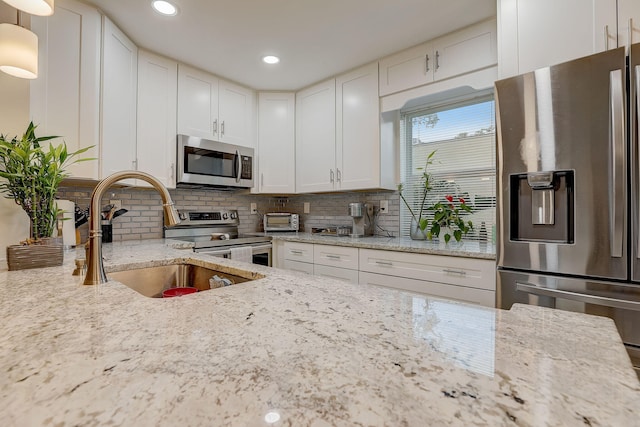 kitchen with stainless steel appliances, light stone countertops, and white cabinets