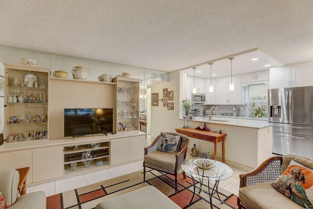 living room with a textured ceiling, light tile patterned floors, and sink