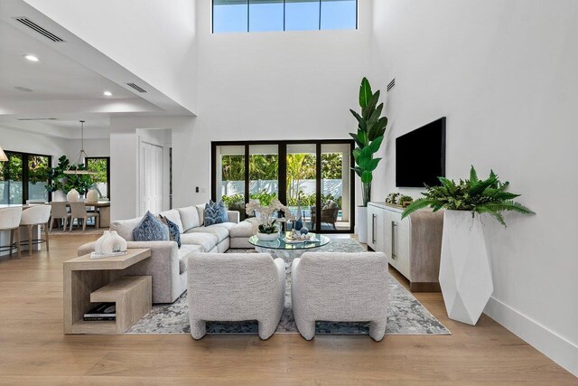 interior space with baseboards, visible vents, wood finished floors, and a towering ceiling
