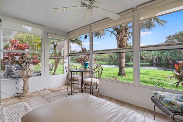 sunroom / solarium featuring a water view and ceiling fan