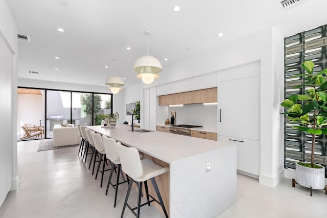 kitchen with white cabinets, decorative light fixtures, and a kitchen island with sink