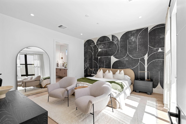 bedroom featuring connected bathroom and light hardwood / wood-style flooring