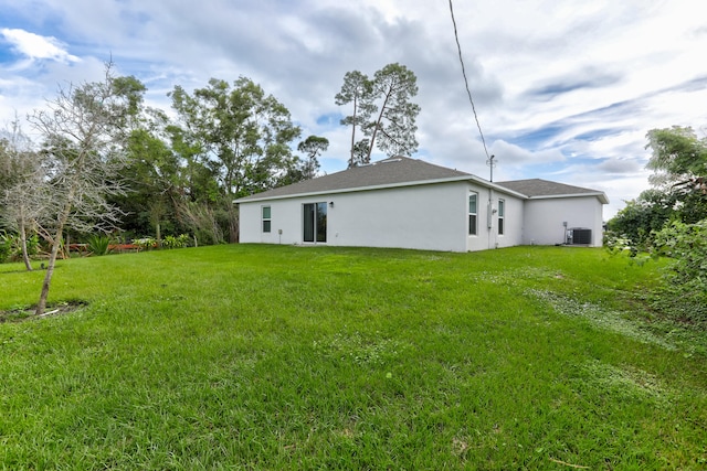 back of property featuring cooling unit and a yard