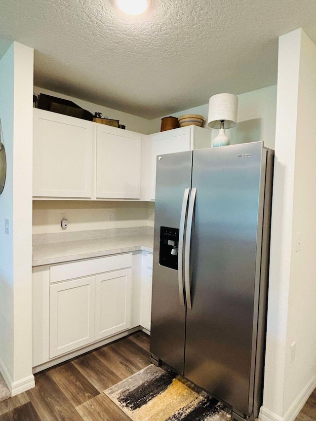 kitchen with stainless steel fridge with ice dispenser, a textured ceiling, white cabinetry, and dark wood-type flooring