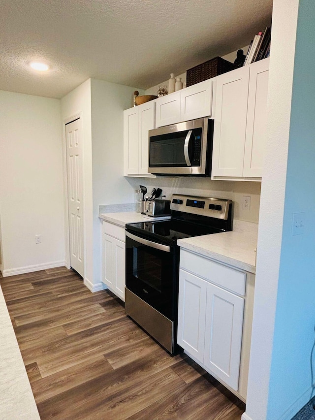 kitchen featuring white cabinets, a textured ceiling, appliances with stainless steel finishes, and dark wood-type flooring