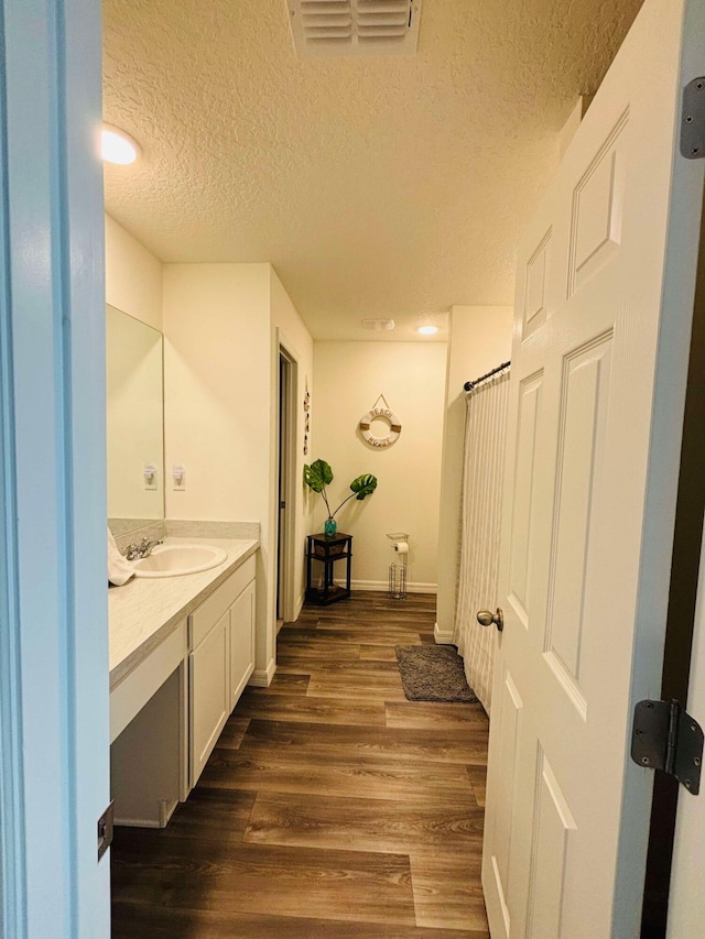 bathroom with hardwood / wood-style flooring, vanity, and a textured ceiling