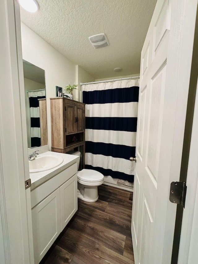 bathroom with hardwood / wood-style flooring, vanity, toilet, and a textured ceiling