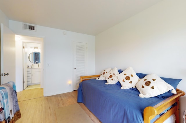 bedroom featuring connected bathroom and hardwood / wood-style flooring