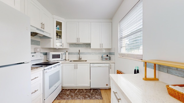 kitchen featuring light hardwood / wood-style floors, white cabinets, sink, tasteful backsplash, and white appliances