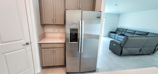 kitchen with stainless steel refrigerator with ice dispenser, gray cabinetry, light tile patterned floors, and decorative backsplash